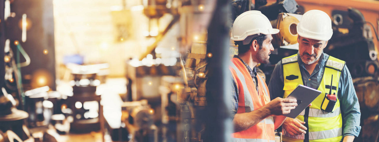 Caucasian factory engineer talking and shaking hands on business cooperation agreement. Successful hand shaking after good deal, workers handshaking each other at heavy industrial production line.