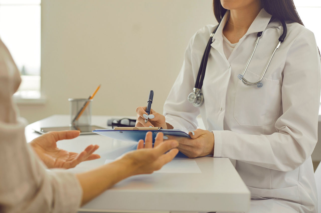 Cropped image of female doctor with clipboard listening to client's health complaints and concerns and noting down symptoms. Therapeutist keeping patient's chart writing down her personal information