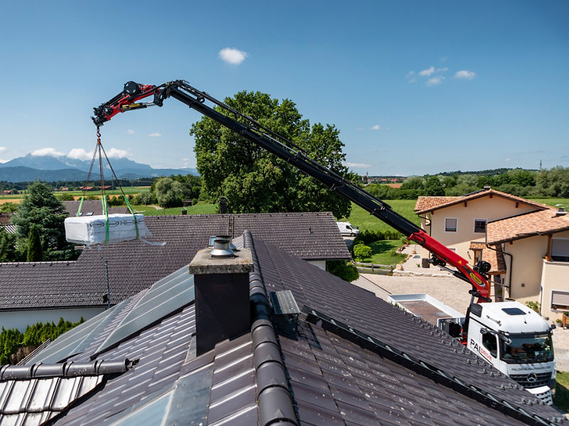 Palfinger TEC loader crane lifting a pallet over a roof