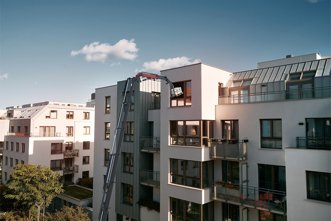 PALFINGER PZP-TILT tilting attachment mounted on a modern residential apartment building – exterior view of the equipment at the building facade with balconies
