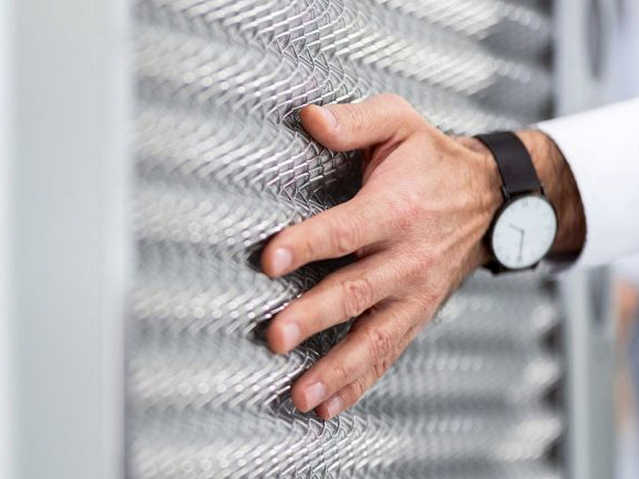 Close-up of a hand touching a textured metal surface, highlighting material quality, precision, and craftsmanship.