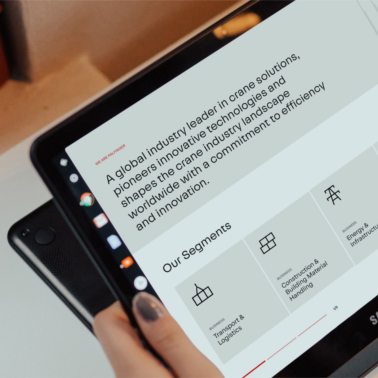 Nahaufnahme eines Tablets, auf dem die Website von PALFINGER angezeigt wird und die Geschäftssegmente und das Unternehmensleitbild hervorgehoben werden.