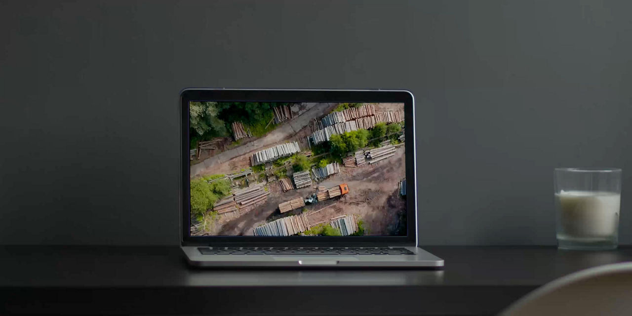 Laptop on a desk displaying an aerial video of an industrial yard with stacked materials and vehicles, accompanied by the text “Motion Guideline,” illustrating motion and video usage in brand communication.