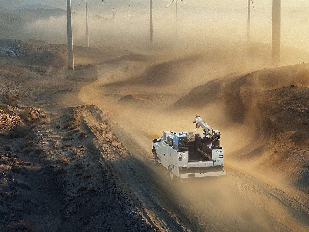 Industriefahrzeug im Einsatz in einer weitläufigen Wüstenlandschaft, von oben betrachtet, wobei Größe, Power und Umweltkontext hervorgehoben werden.
