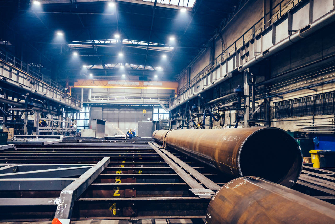 Pipes and steel profiles in a big factory. Workers welding. Shipyard, heavy industry, Pipes and steel profiles in a big factory. Workers welding. Shipyard, heavy industry