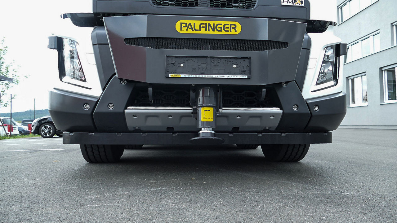 Front view of a Volvo FMX truck with a factory-mounted PALFINGER front stabilizer mounting kit, showing the underside of the front bumper and coupling receiver.