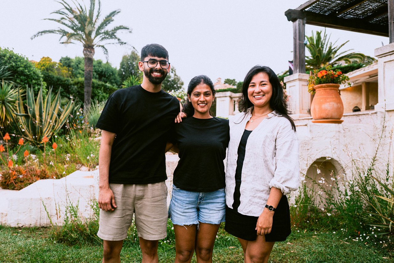 Spark Academy 2025 in Cannes: Three young people standing arm in arm in front of a Mediterranean garden, smiling at the camera.