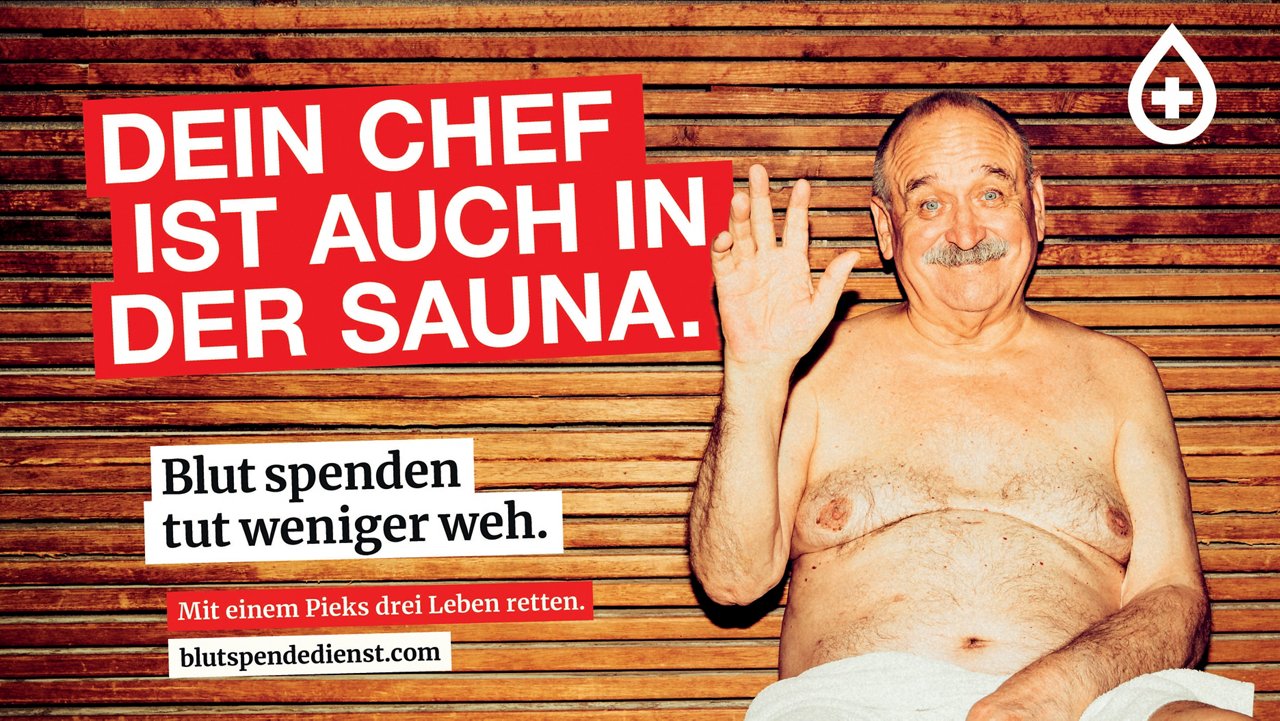 Ein älterer, lachender Mann sitzt mit Handtuch in der Sauna und winkt. Text: „DEIN CHEF IST AUCH IN DER SAUNA.“ sowie Aufruf zur Blutspende mit Website „blutspendedienst.com“. Logo des Bayerischen Roten Kreuzes oben rechts.