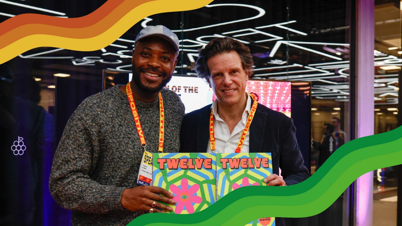 Florian Haller, CEO der Serviceplan Group, und Yinka Ilori, Designer: Das Bild zeigt zwei Männer, die herzlich in die Kamera lächeln und ein Magazin präsentieren, auf dem der Titel TWELVE zu lesen ist. Das Cover zeigt eine Neon-Illustration in Pink, Grün und Gelb.