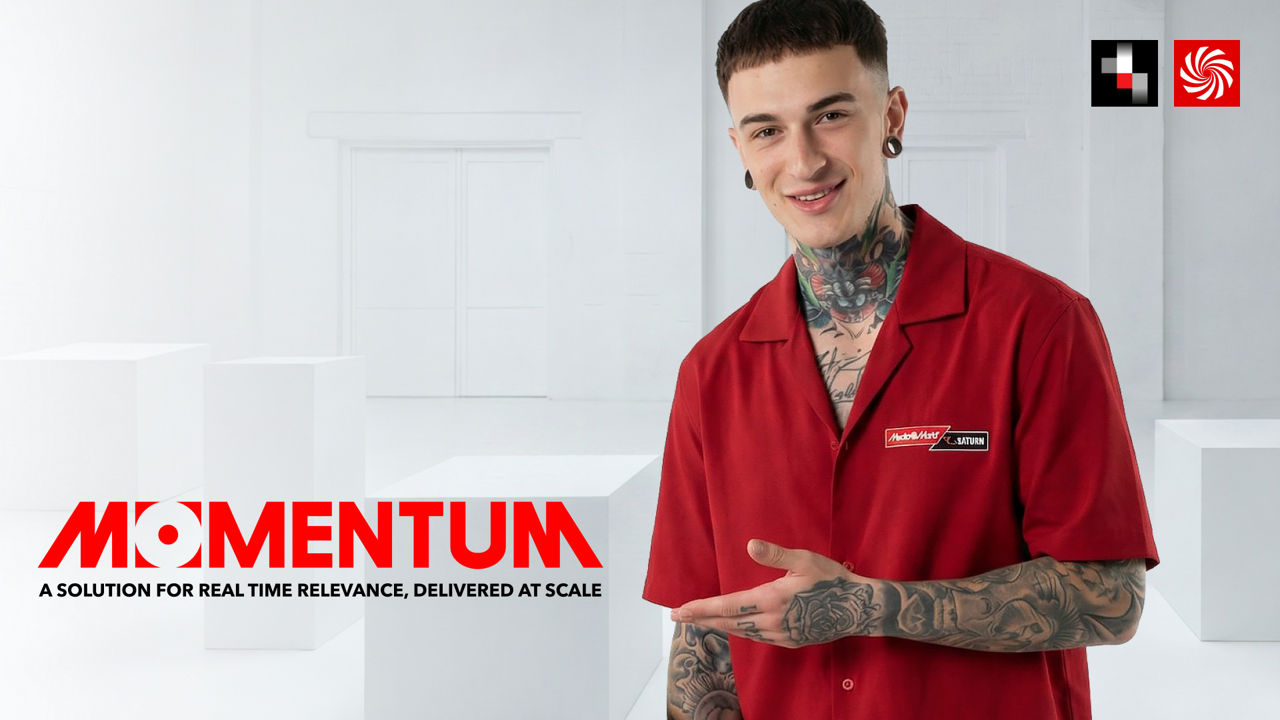 Promotional visual for “Momentum”: A tattooed person wearing a red shirt stands against a bright background, pointing toward the text “Momentum – A Solution for Real Time Relevance, Delivered at Scale.”