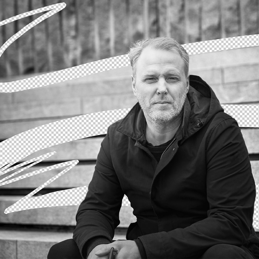 Michael Wilk sitting outdoors in a black and white portrait, wearing a dark jacket.