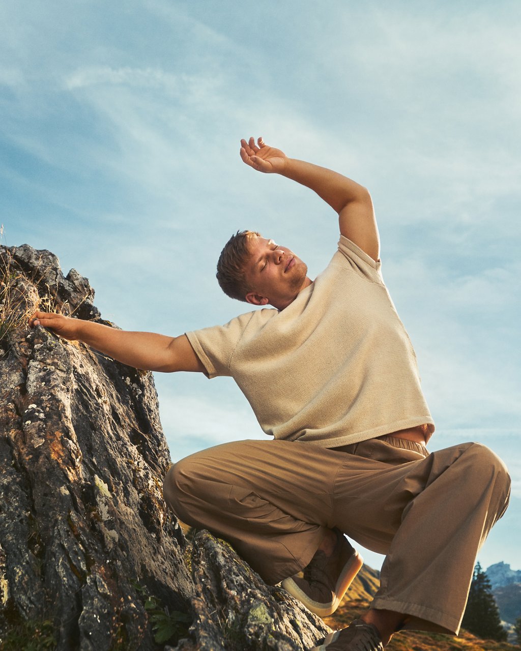 Tanzender Mann vor blauem Himmel in einer alpinen Landschaft
