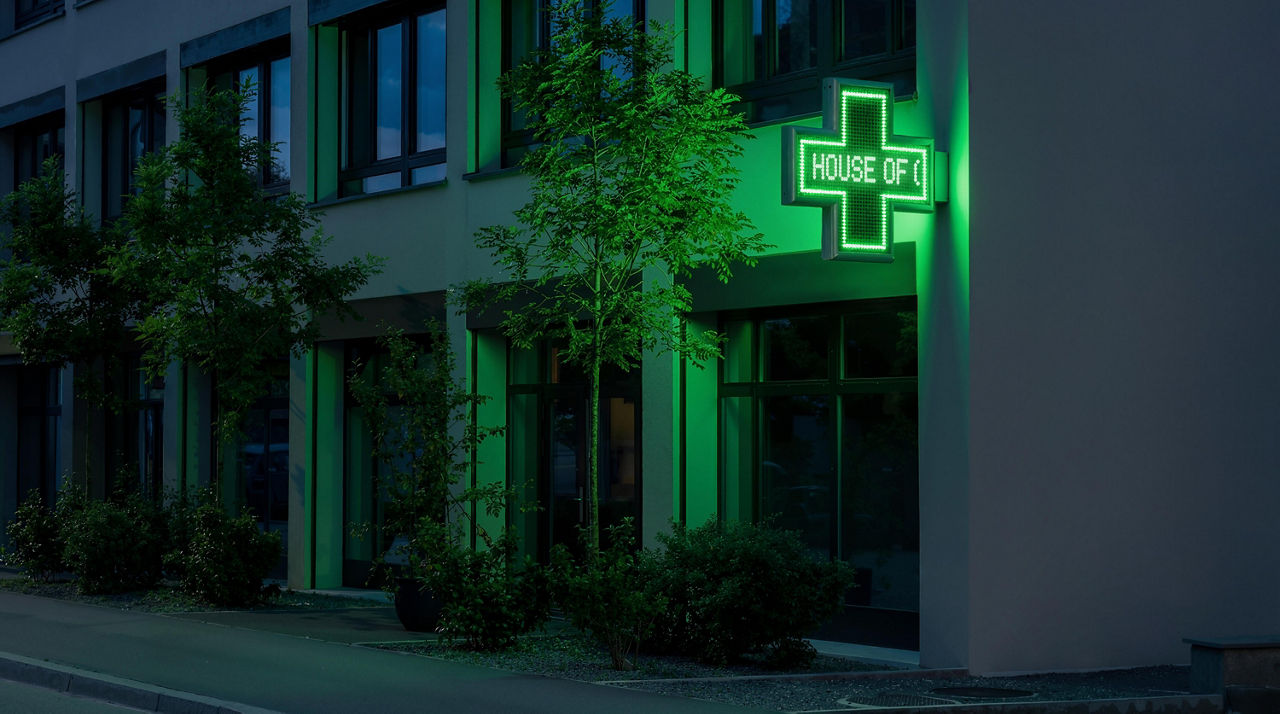 Ein Bild des House of Communication Zürich, auf dem eine gründe Apothekertafel angebracht ist in der Nacht