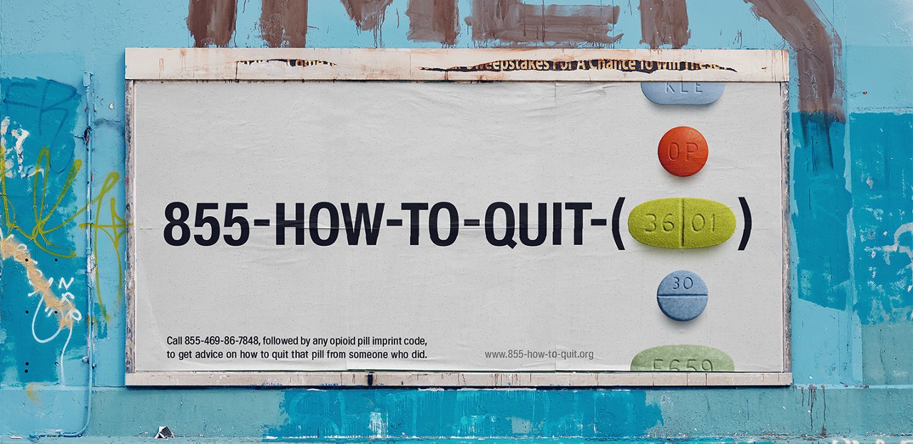 Advertising poster on a building wall of Anzen Health on which opioids are lined up vertically in the form of various pills, and next to them is a telephone number '855-HOW-TO-QUIT', which indicates advice on quitting medications or substances