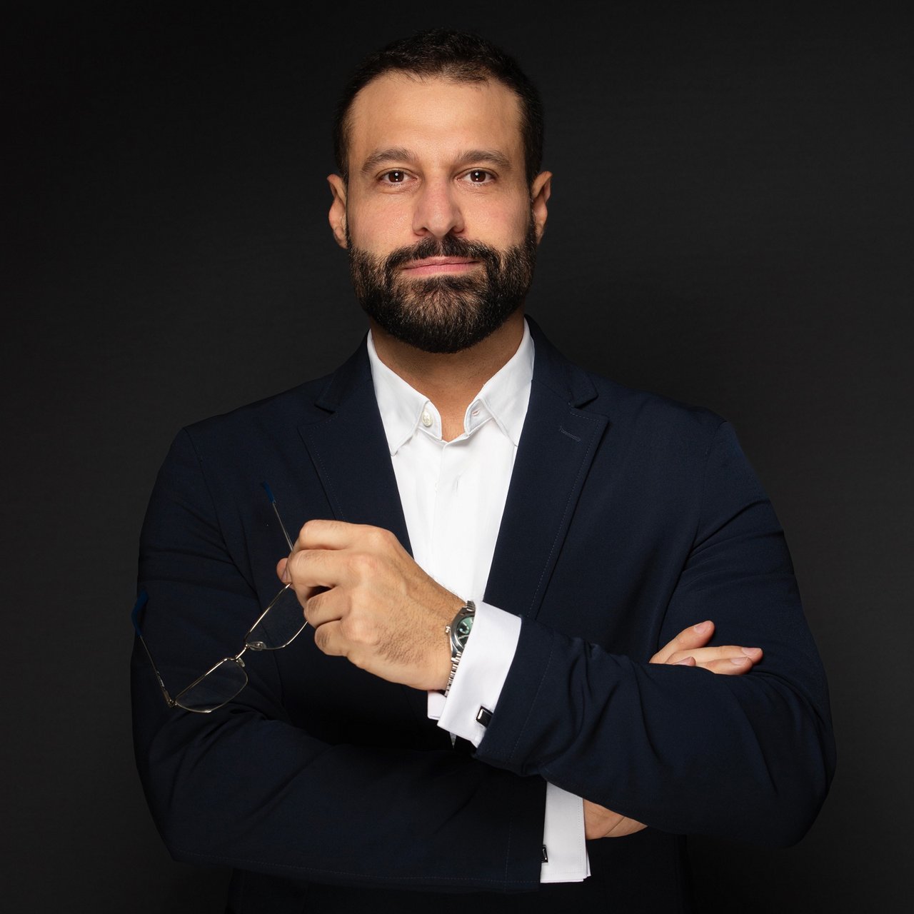 Hicham Soubra, Head of Production at Serviceplan Arabia: A man with dark hair and a beard is wearing a white shirt and dark suit against a black background.