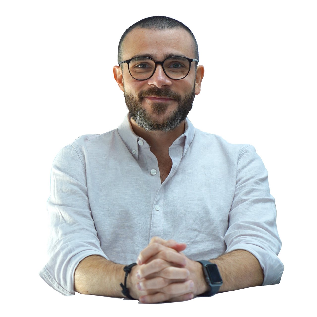 Tareq Almasri: a man with a neatly trimmed beard and glasses is smiling at the camera. He is wearing a light-colored button-up shirt with the sleeves rolled up and has his hands clasped in front of him. The background is plain white, placing full focus on the subject.