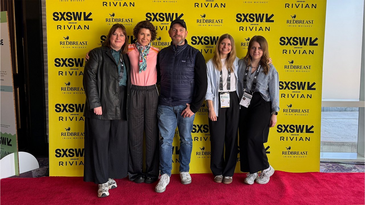 Five people stand together on a red carpet in front of a yellow SXSW backdrop with logos of SXSW, Rivian, and Redbreast. All are wearing event badges and facing the camera.