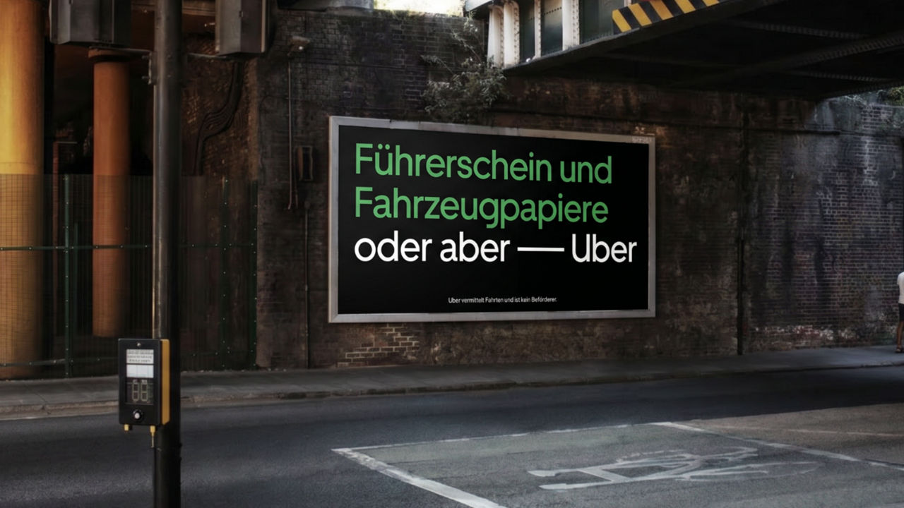 Großes Uber-Werbeplakat unter einer Brücke mit dem Text ‚Führerschein und Fahrzeugpapiere oder aber — Uber‘.