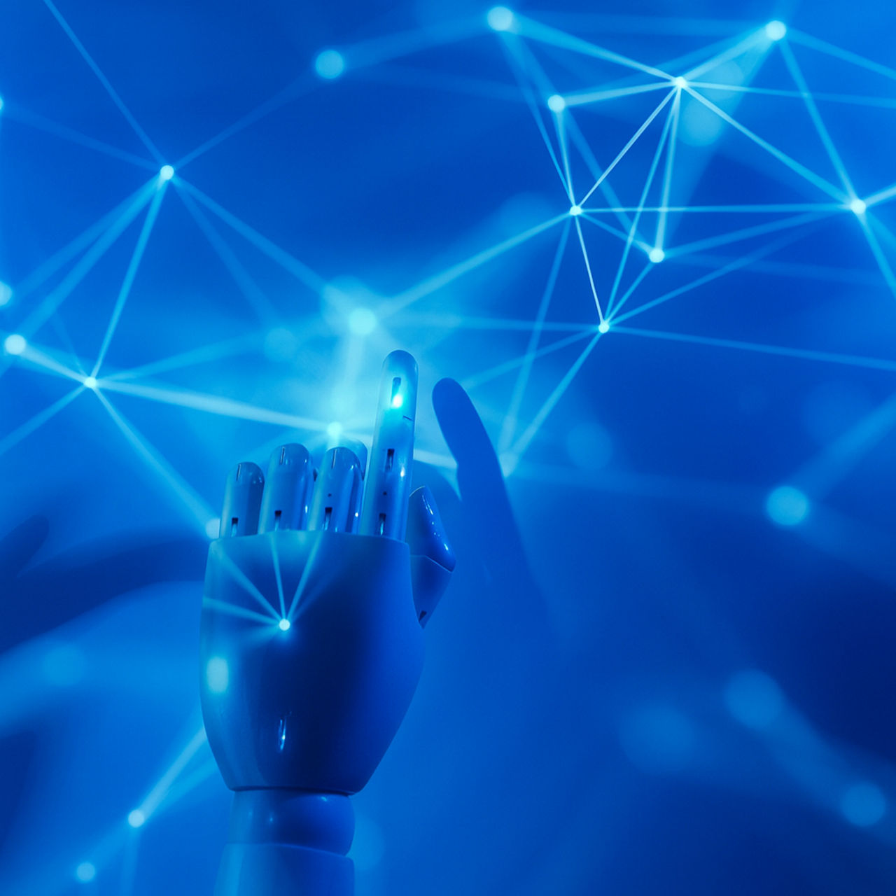 A robotic hand reaches toward a glowing blue digital network of interconnected nodes and lines