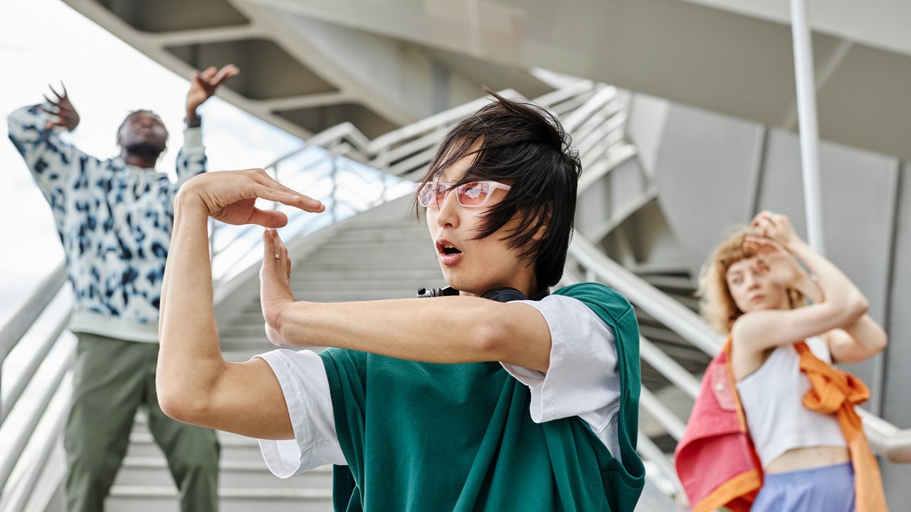 Three young people dancing outdoors on urban steps in expressive, individual styles