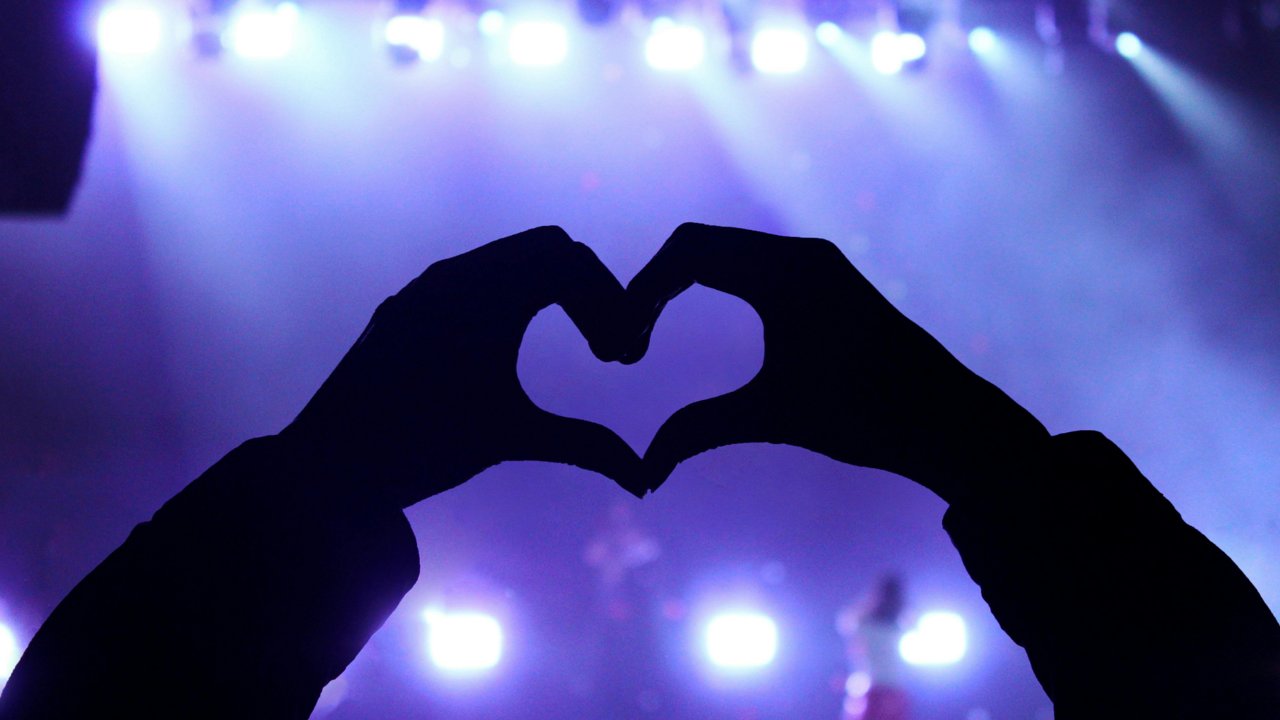 Two hands shaped as heart in fromt of a stage