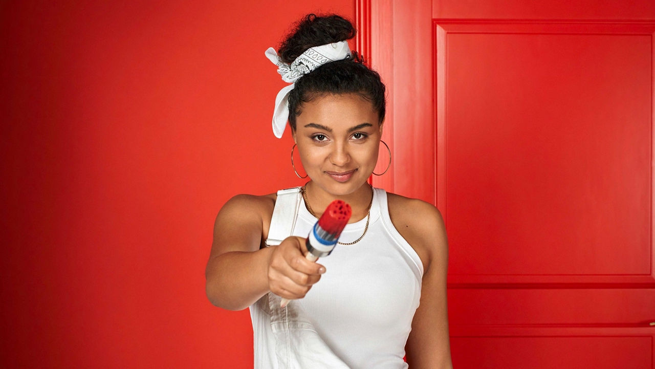 Young lady in painter's clothes with a paintbrush in her hand