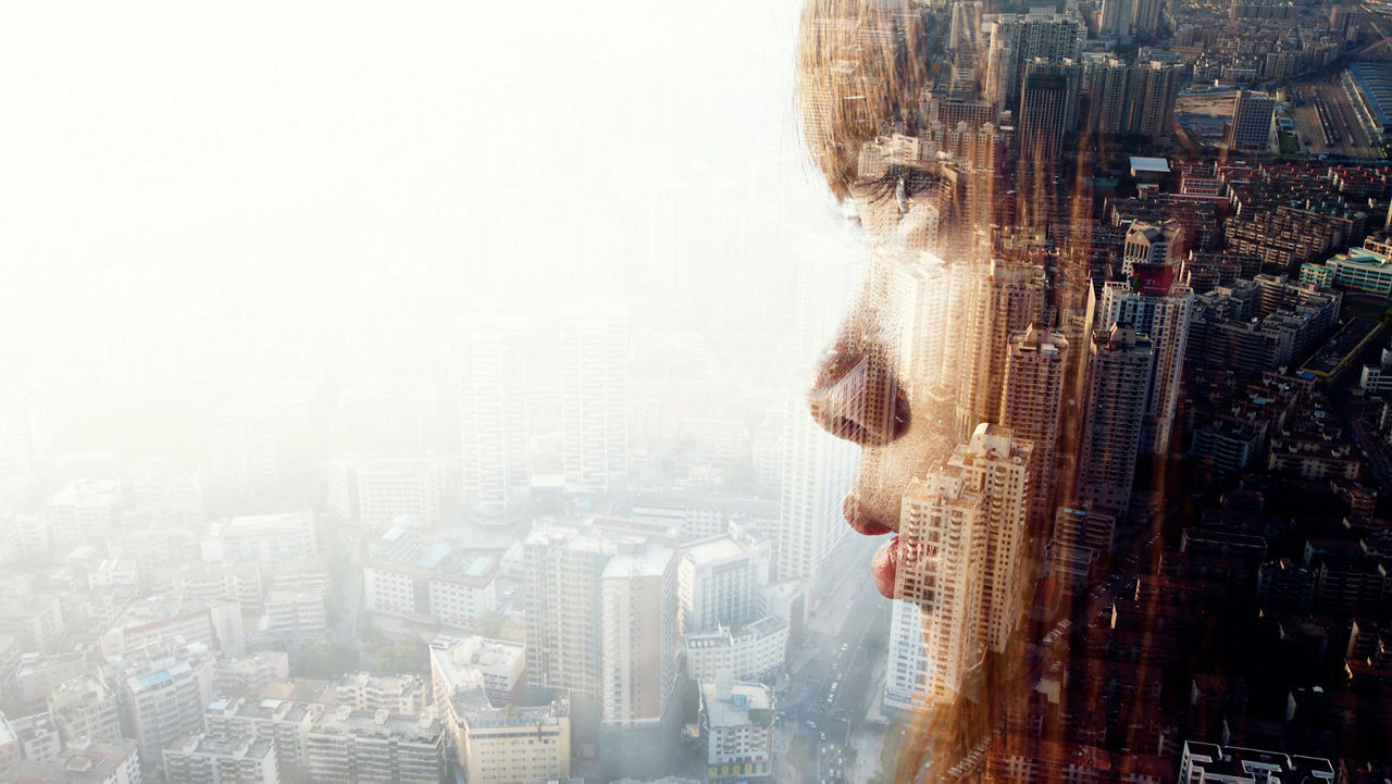 The face of a woman superimposed on a cityscape in daylight symbolises the connection between people and their urban surroundings