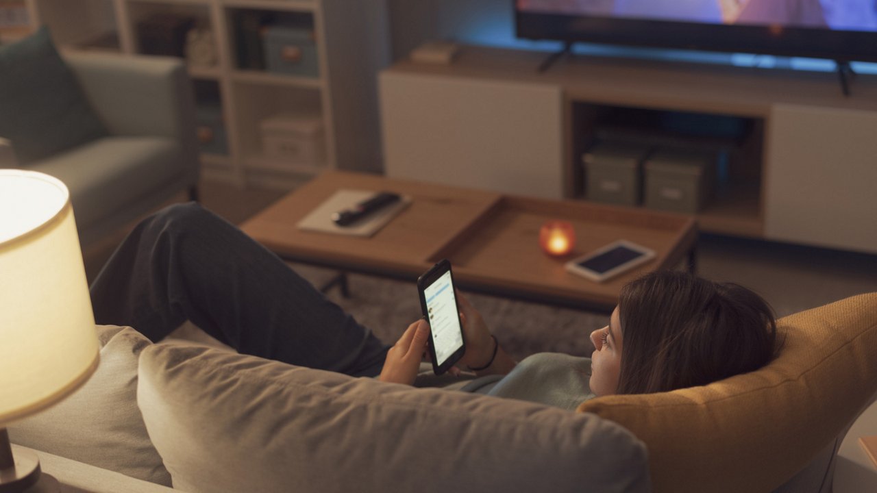 Adolescent girl lying down on the couch with her smartphone