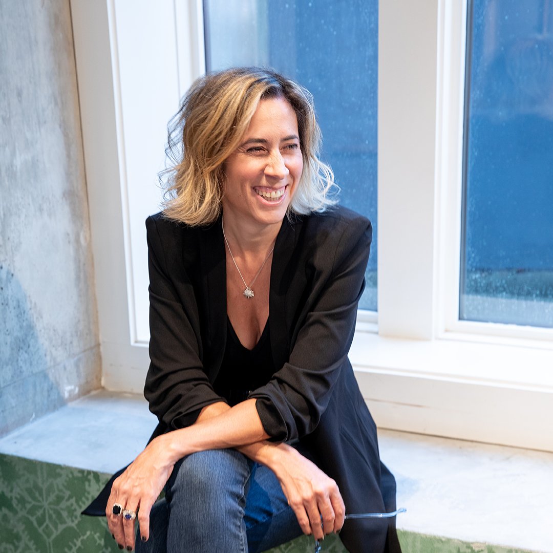 A woman sitting in front of a window smiling