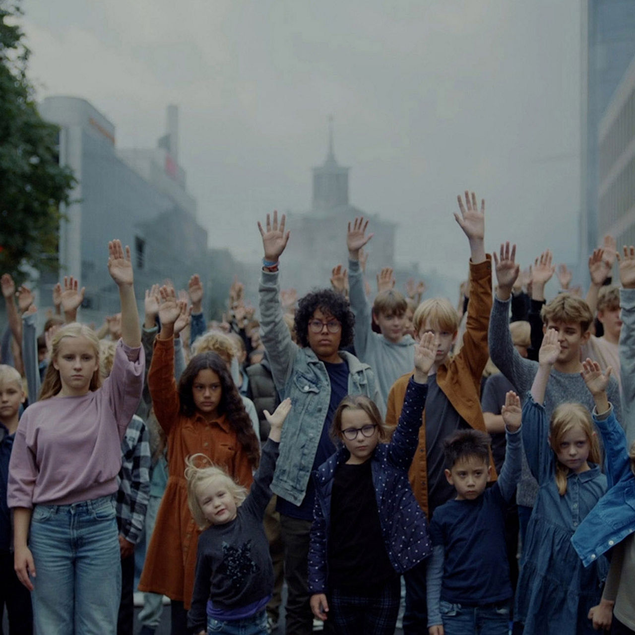 PENNY - The Kids - Eine große Gruppe von Kindern unterschiedlichen Alters und Geschlechts steht mit ernsten Mienen zusammen. Alle haben den rechten Arm erhoben welches symbolisiert, Kindern und Jugendlichen eine Stimme zugeben und ihnen zu zuhören