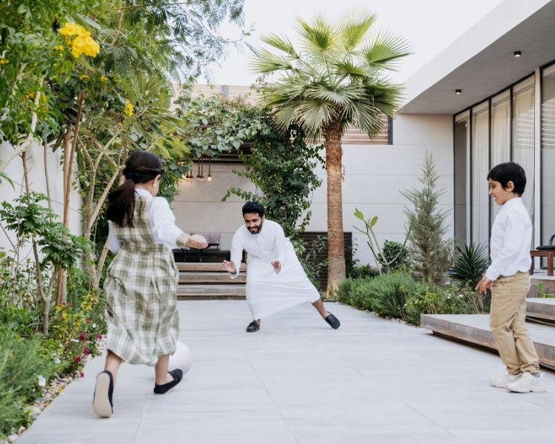 Qiddiya City exemplar homes showcasing modern residential living, with people walking through a landscaped courtyard surrounded by contemporary architecture and greenery