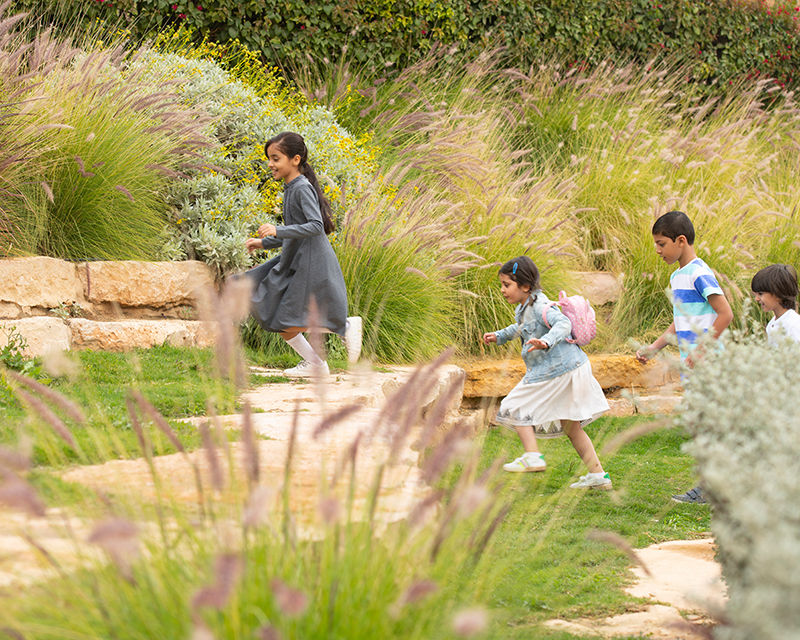 Qiddiya City community section highlighting inclusive living, diversity, and lifestyle, with people walking through a green landscaped park promoting connection and outdoor experiences