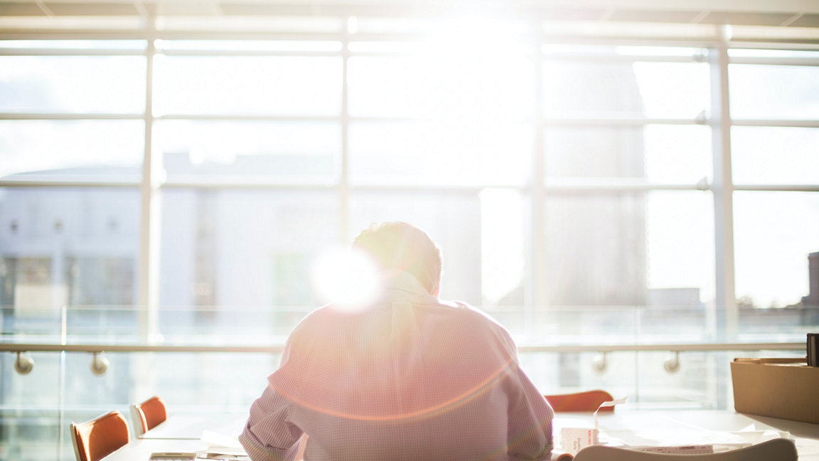 Man sat at desk in front of window with sun flare