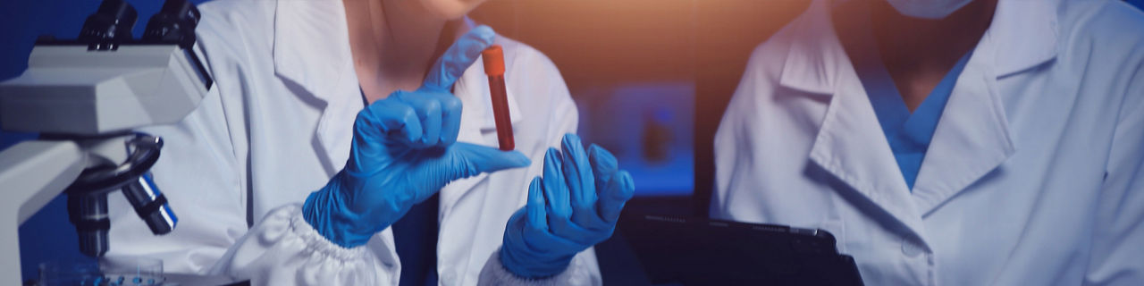 Profesionales de laboratorio analizando muestras de sangre al microscopio y con tubos de ensayo para identificar nuevos 