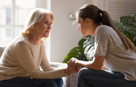 Grown up daughter holding hands of middle aged mother relatives female sitting look at each other having heart-to-heart talk, understanding support care and love of diverse generations women concept (Grown up daughter holding hands of middle aged moth