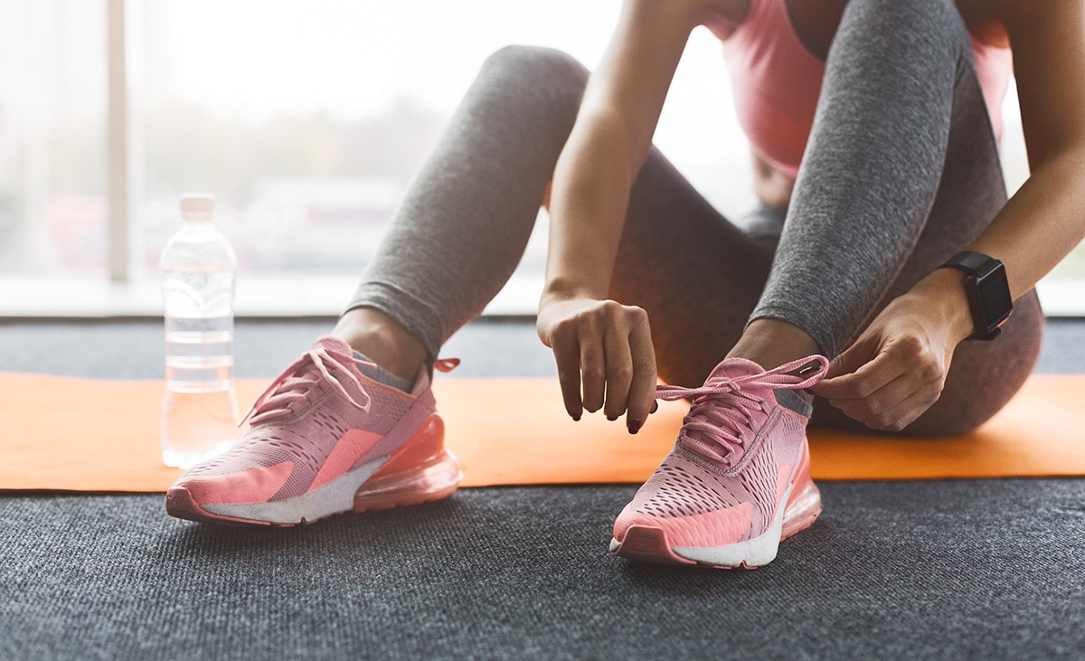 Woman tying laces preparing for training, wearing sneakers, crop, closeup