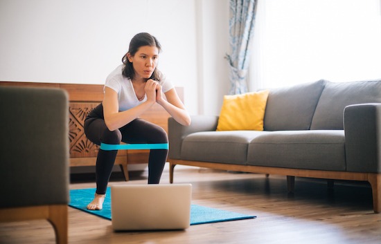 Sporty young woman exercising at home with resistance band