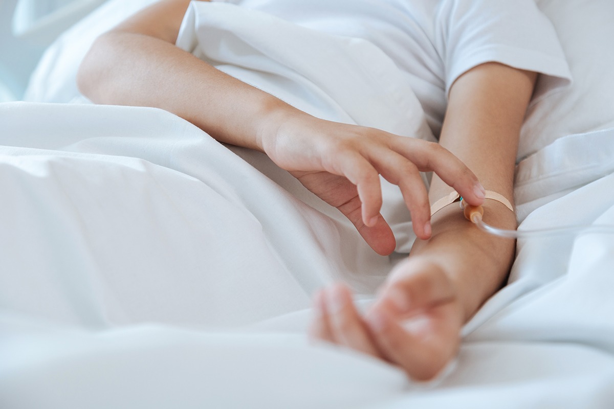 IV therapy. Close up of a catheter being inserted in the patients vein while being hooked up to an IV