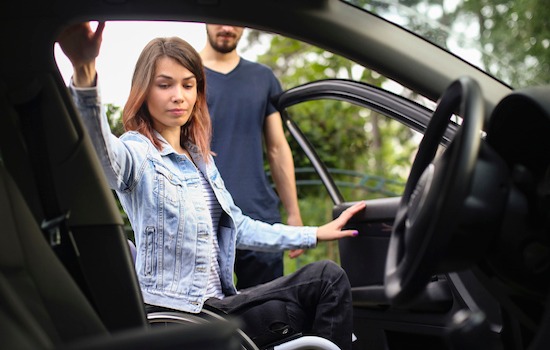 Disabled young woman and her boyfriend getting into a car. Both about 25 years old, Caucasian people.