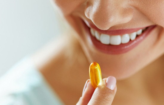 Vitamin And Supplement. Closeup Of Beautiful Young Woman Taking Yellow Fish Oil Pill. Female Hand Putting Omega-3 Capsule In Mouth. Healthy Eating And Diet Nutrition Concepts. High Resolution Image (Vitamin And Supplement. Closeup Of Beautiful Young W