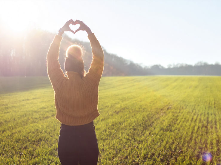 Junge Frau formt mit beiden Händen ein Herz