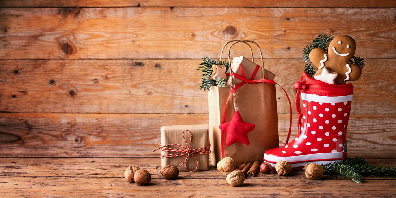 Santa´s shoe  -  Stuffed Santa Claus boot -  Gumboot,  paper bag, gift boxes and gingerbread man on rustic wood background  -  Christmas card 