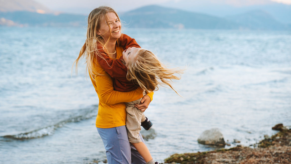 Family lifestyle Mom playing with daughter having fun outdoor travel together summer vacations woman with child at the lake Mothers day holiday happy emotions
