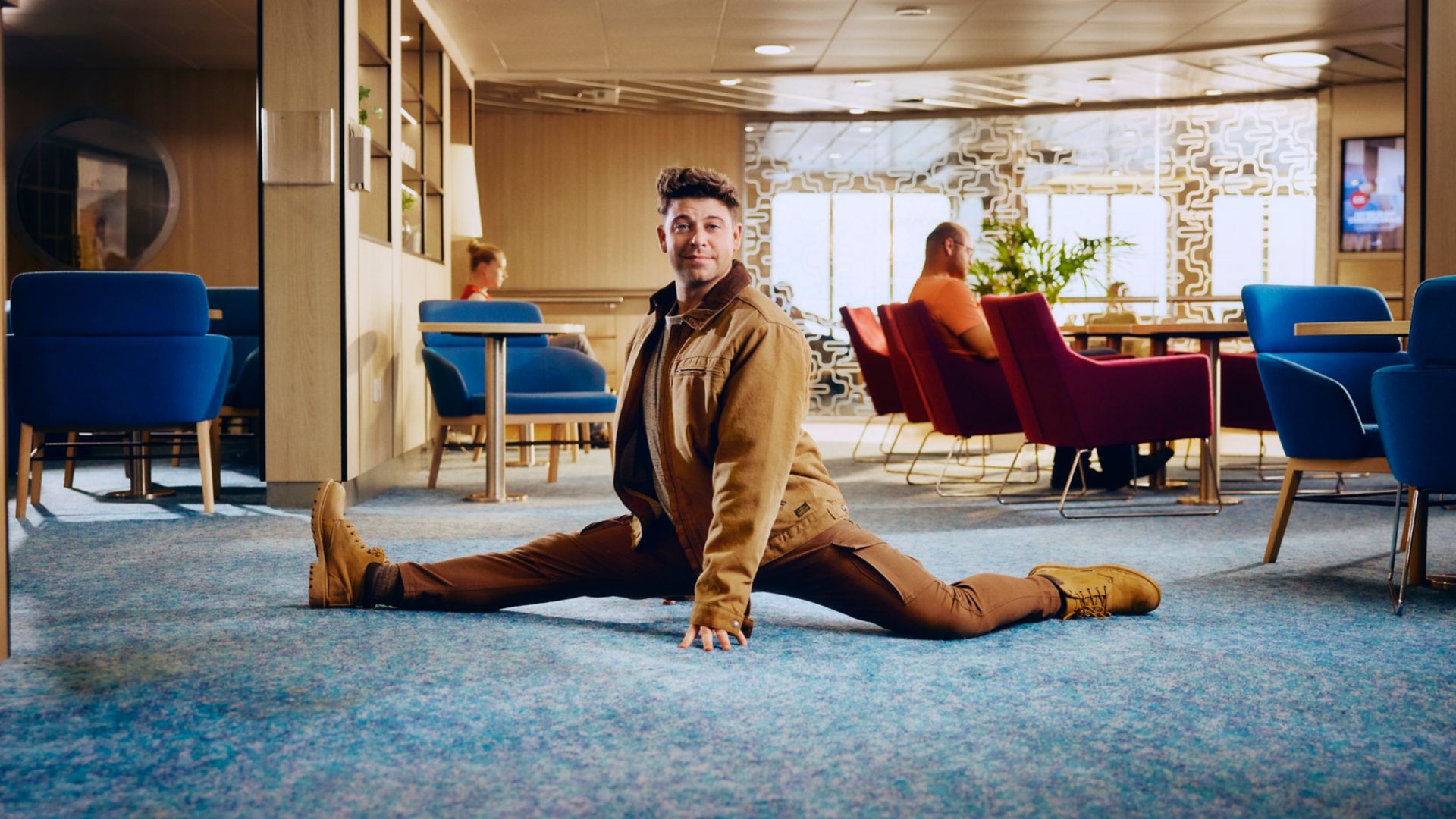 Man stretching in Stena Line ferry lounge, relaxed onboard travel atmosphere