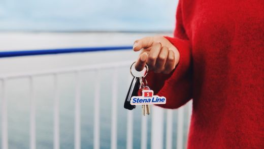 Person håller bilnycklar med Stena Line-nyckelring på färjedäck och är redo för en smidig vidare resa