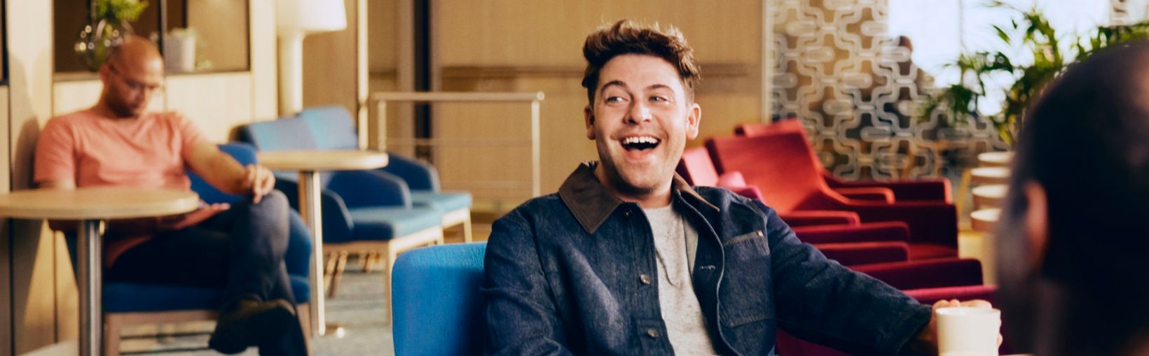 Man smiling and chatting in a cozy lounge with coffee and colorful seating