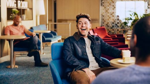 Man smiling and chatting in a cozy lounge with coffee and colorful seating