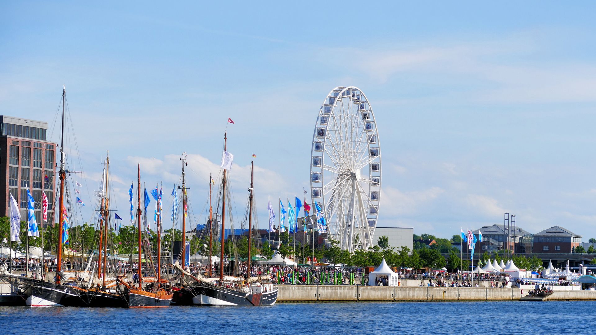 Kaianlage während der Kieler Woche mit Segelschiffen und Riesenrad, lebendige maritime Festivalstimmung