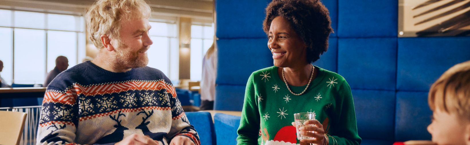 Family enjoying Christmas buffet onboard ferry in festive jumpers during their holiday crossing