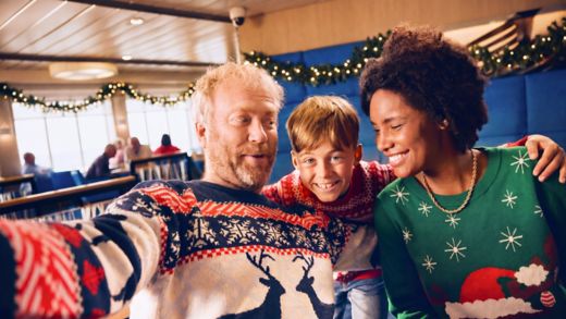 AI Generate image. A cheerful family of three poses closely together for a selfie, all wearing colourful Christmas sweaters. They are on board a ferry in a lounge decorated with garlands and holiday lights.